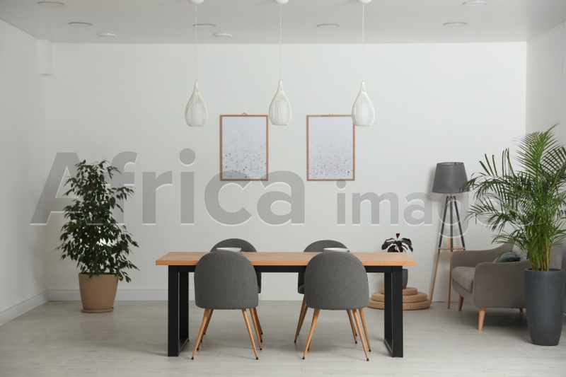 Photo of Stylish wooden table and chairs in light room. Modern interior design