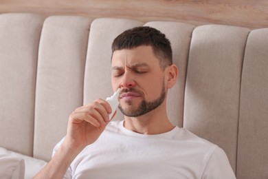 Ill man using nasal spray in bed at home