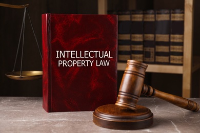 Intellectual Property law book and judge's gavel on grey marble table