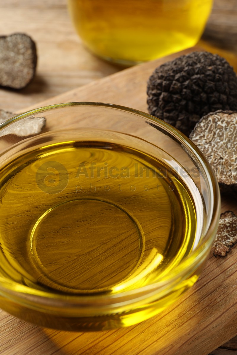 Glass bowl of truffle oil on wooden board, closeup