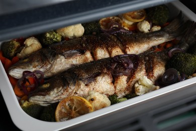 Photo of Baking tray with sea bass fish and vegetables, closeup