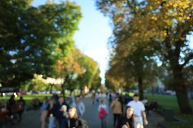 Photo of Blurred view of people walking in park on sunny day