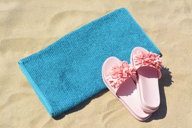 Photo of Towel and flip flops on sand, above view. Beach accessories