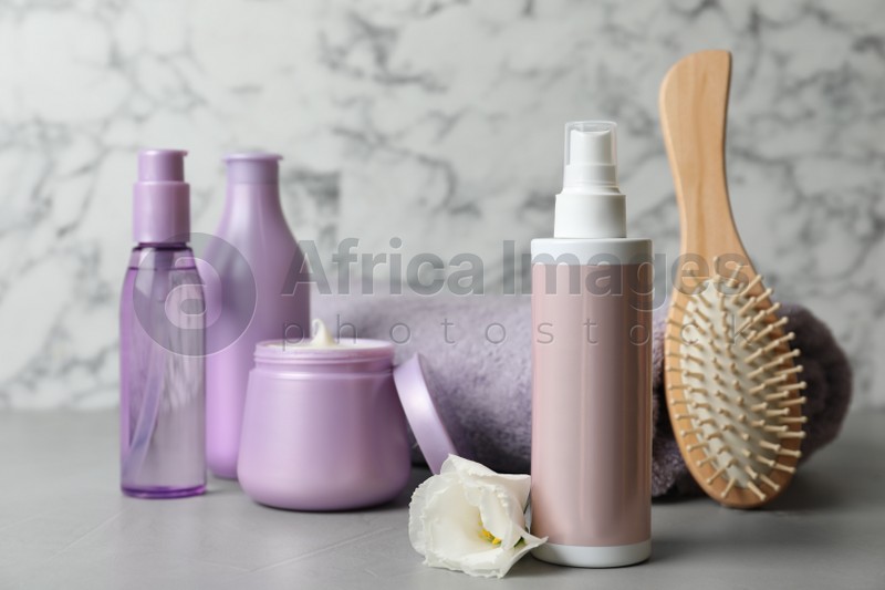 Different hair products, towel and brush on grey table