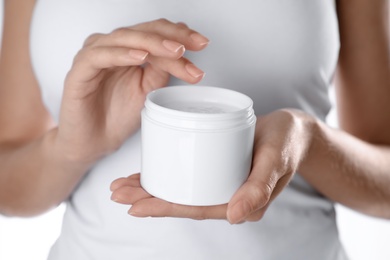 Woman with jar of moisturizing cream on white background, closeup