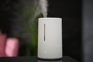 Modern air humidifier on table at home