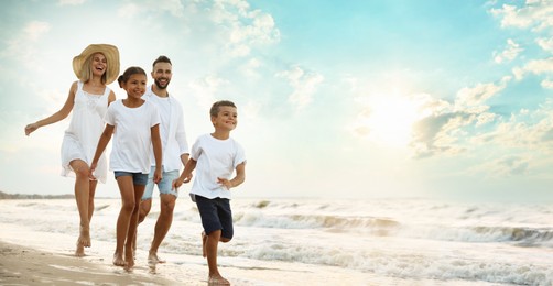 Image of Happy family walking on sandy beach near sea at sunset, space for text. Banner design