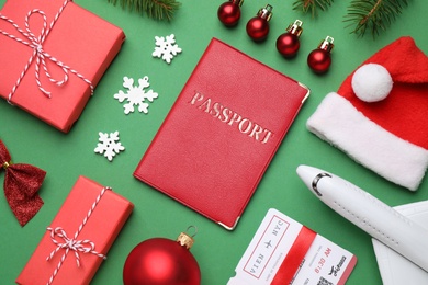 Flat lay composition with toy airplane, passport and festive decor on green background. Christmas vacation
