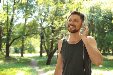 Photo of Handsome man with headphones on run in park, space for text. Morning exercise