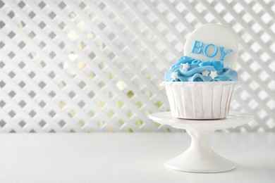 Photo of Delicious cupcake with light blue cream and Boy topper on white table, space for text. Baby shower party