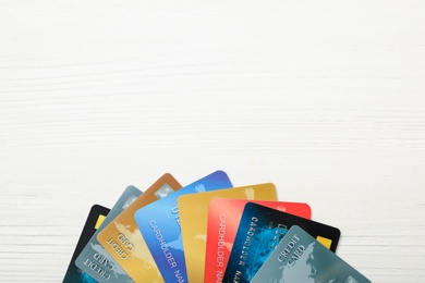 Many different credit cards on white wooden table, flat lay. Space for text