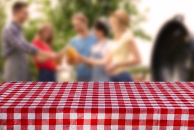 Image of Table with checkered picnic cloth outdoors on sunny day. Space for design