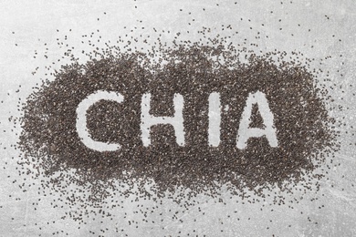 Photo of Word CHIA written in pile of seeds on grey table, top view