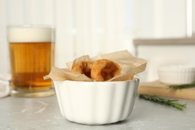 Delicious crunchy fried onion rings on grey marble table indoors