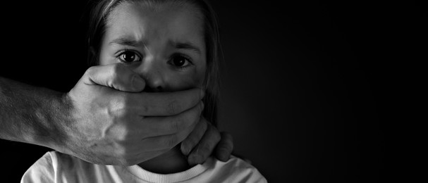 Man covering scared little girl's mouth on black background, space for text. Domestic violence. Banner design