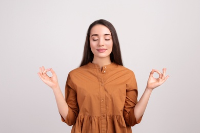 Young woman meditating on beige background. Stress relief exercise