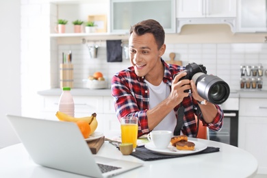 Portrait of food blogger with laptop and camera in kitchen. Online broadcast