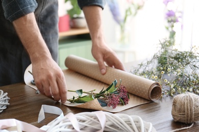 Male florist creating beautiful bouquet at table, closeup