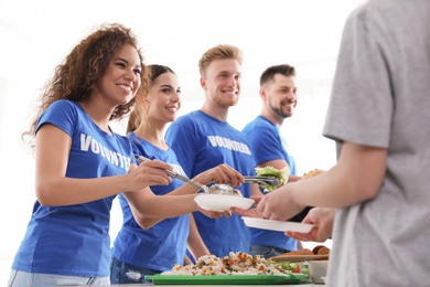 Volunteers serving food to poor people indoors