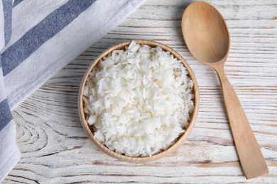 Bowl with tasty cooked rice on white wooden table, flat lay