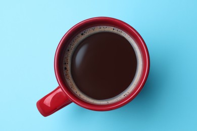 Photo of Red mug of freshly brewed hot coffee on light blue background, top view