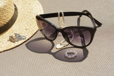 Stylish hat, sunglasses and jewelry on grey surface, closeup