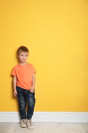 Portrait of cute little boy against color wall with space for text
