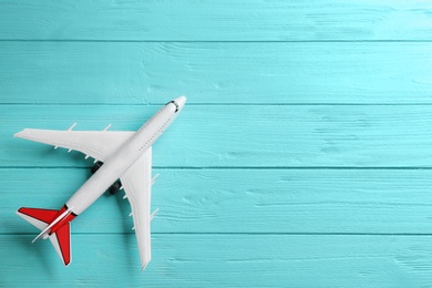 Photo of Toy airplane on light blue wooden background, top view. Space for text