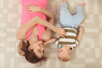 Photo of Young woman with her son lying on floor at home, top view