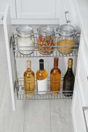Photo of Open drawer with jars of food and wine bottles in kitchen
