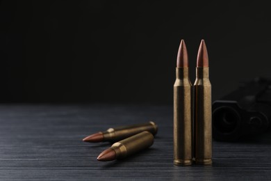 Bullets and pistol on black wooden table. Space for text