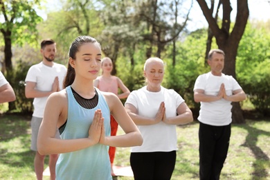 Photo of Group of people practicing yoga in park on sunny day