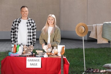 Happy family selling different items on garage sale in yard