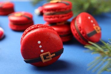 Beautifully decorated Christmas macarons on blue background, closeup. Space for text