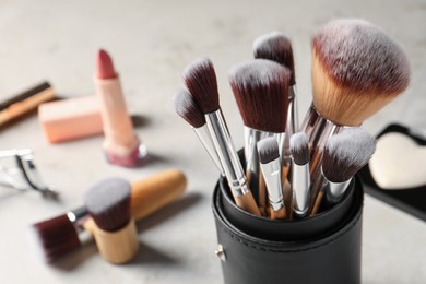 Photo of Set of professional brushes and makeup products on grey table, closeup. Space for text