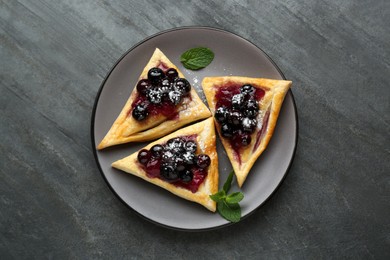 Photo of Fresh tasty puff pastry with sugar powder, jam, sweet berries and mint on grey table, top view