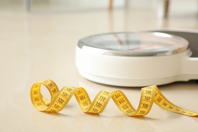 Scales and measuring tape on floor in bathroom. Overweight problem