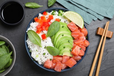 Delicious poke bowl with salmon, spinach and avocado served on black table, flat lay