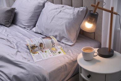 Magazine on bed with soft silky bedclothes in room