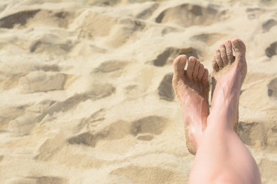 Woman resting on sandy beach, closeup of feet. Space for text