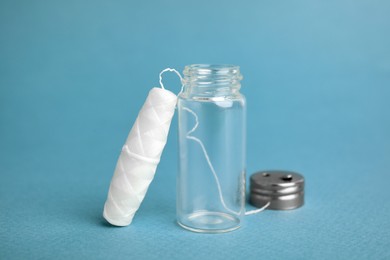 Biodegradable dental floss and glass jar on light blue background