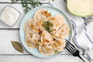 Photo of Cooked dumplings (varenyky) with tasty filling, fried onions and dill on wooden table, flat lay
