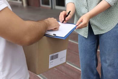 Woman signing for delivered parcel outdoors, closeup