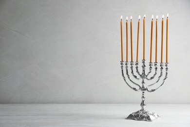 Hanukkah menorah on table against light background
