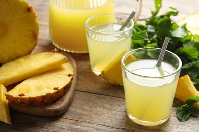 Delicious pineapple juice and fresh fruit on wooden table