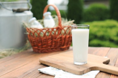 Tasty fresh milk in glass on wooden table outdoors. Space for text