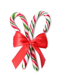 Sweet Christmas candy canes with red bow on white background, top view