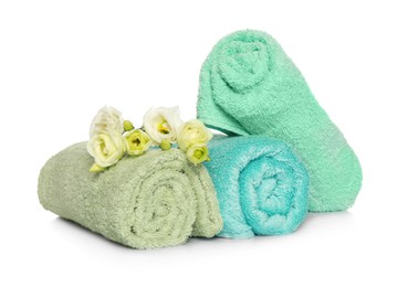 Rolled soft terry towels and flowers on white background