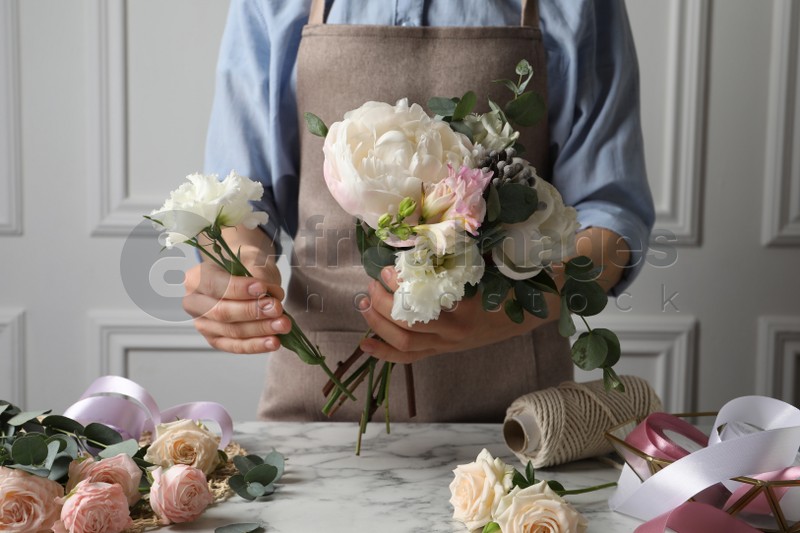 Florist creating beautiful bouquet at white marble table, closeup