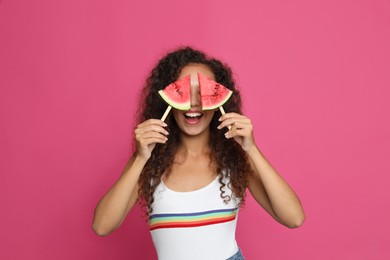 Beautiful young African American woman with pieces of watermelon on crimson background